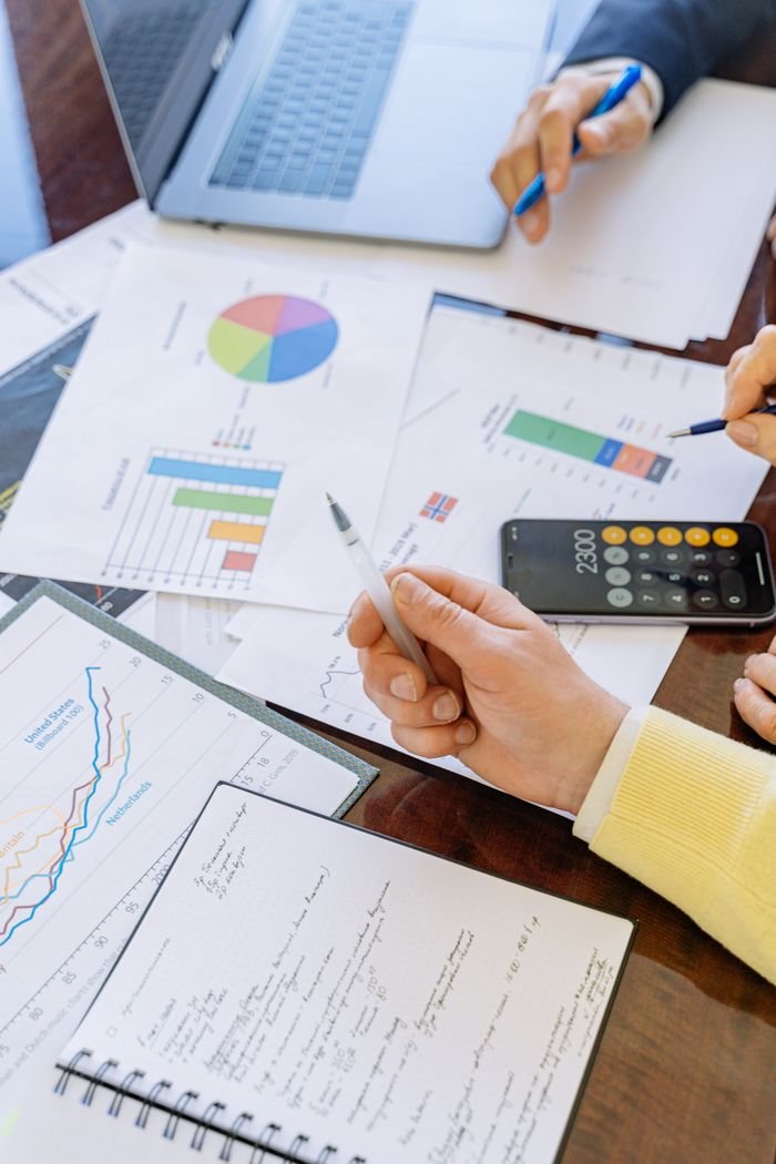 gallery-3 A close-up of businesspeople analyzing financial data and charts during a meeting.