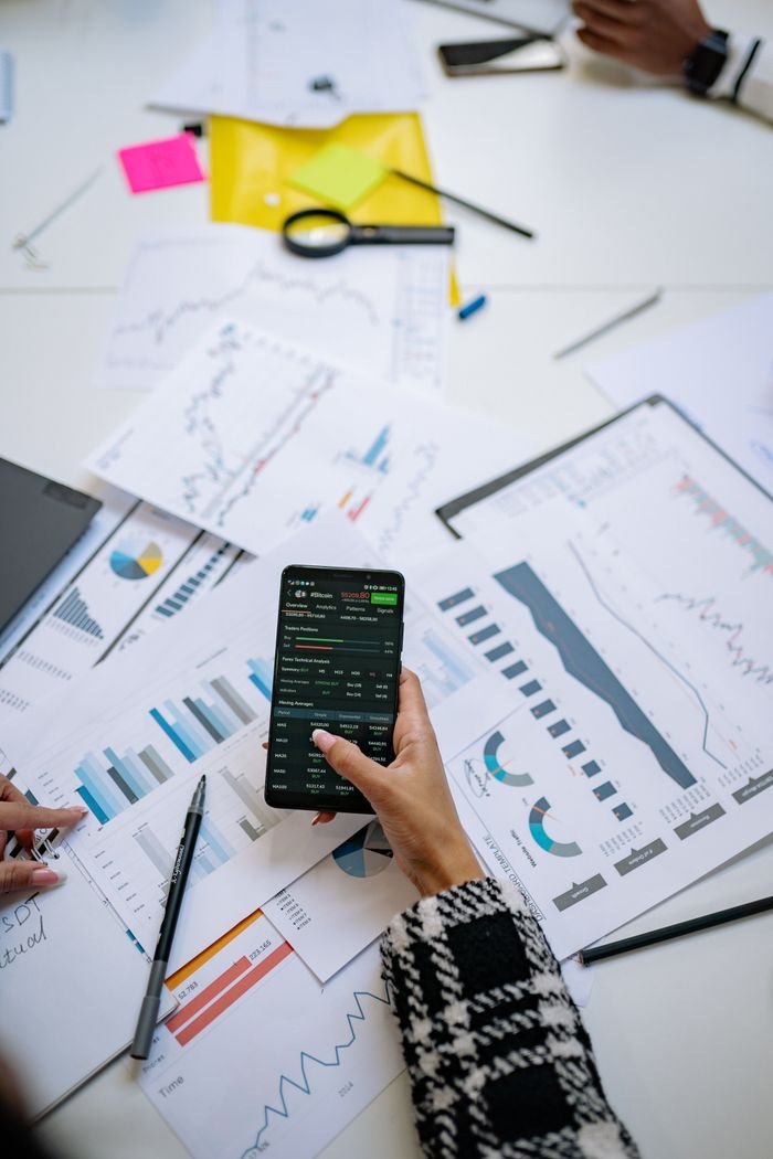 our-experience Person analyzes financial charts using a smartphone in an office setting.
