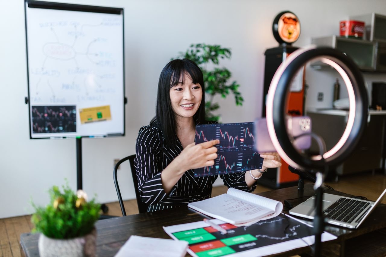 gallery-4 Asian woman discussing cryptocurrency investment during a vlogging session with charts.